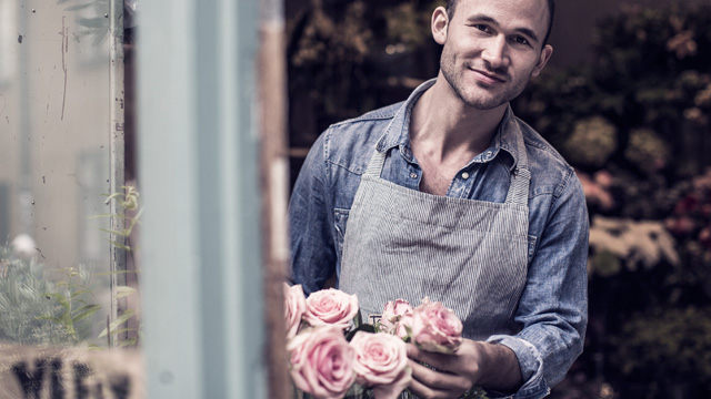 Man works with roses smilling and looking out of the window