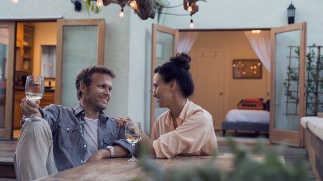 Couple sitting outside their house smiling - Small