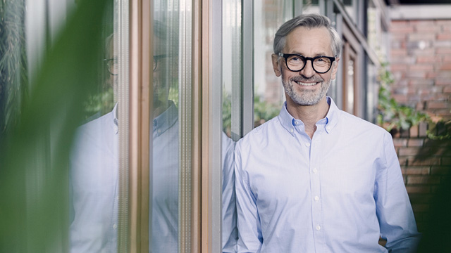 Man smiling leaning against the house