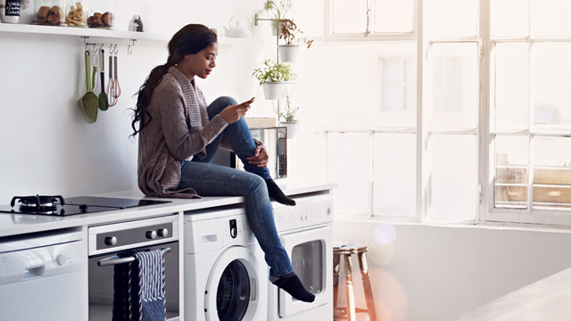 Woman sitting on washing machine 