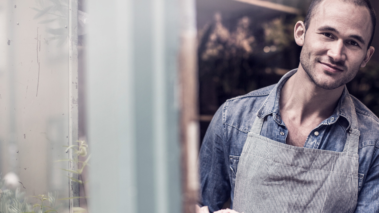 Man works with roses smilling and looking out of the window