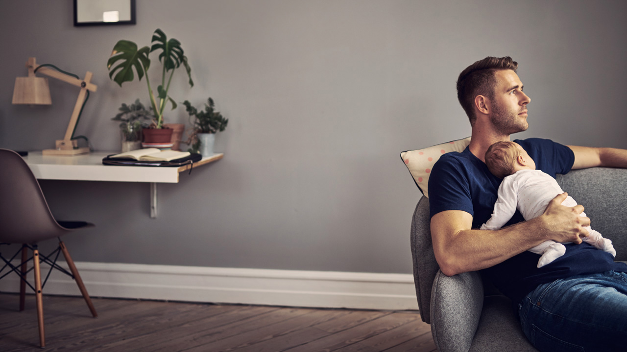 Man resting on sofa with kid resting on his chest 