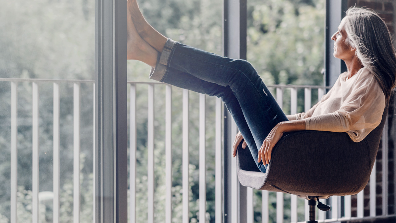 Woman in an armchair resting her feet against a glass wall