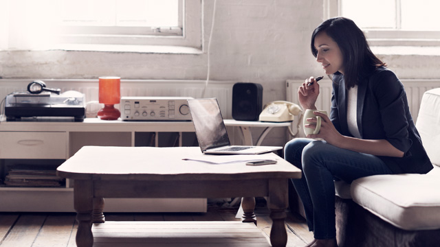 Young woman at home smiling when looking at her laptop