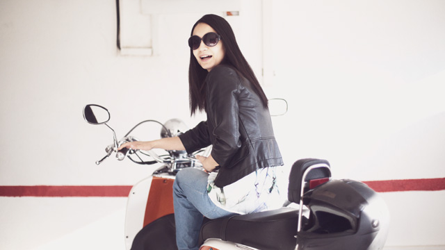 A girl on a scooter in a garage. 