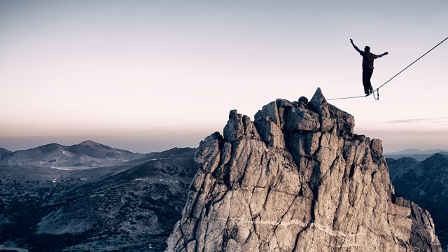 Man balancing on slackline high in the mountains