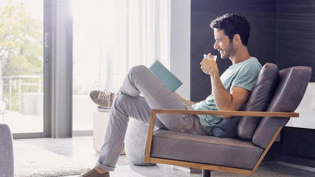 Mann drikker te og leser i en bok
