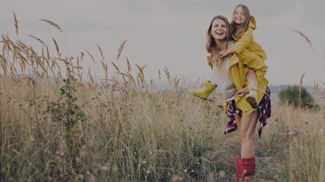 mother in meadow with daughter on her back small overlay