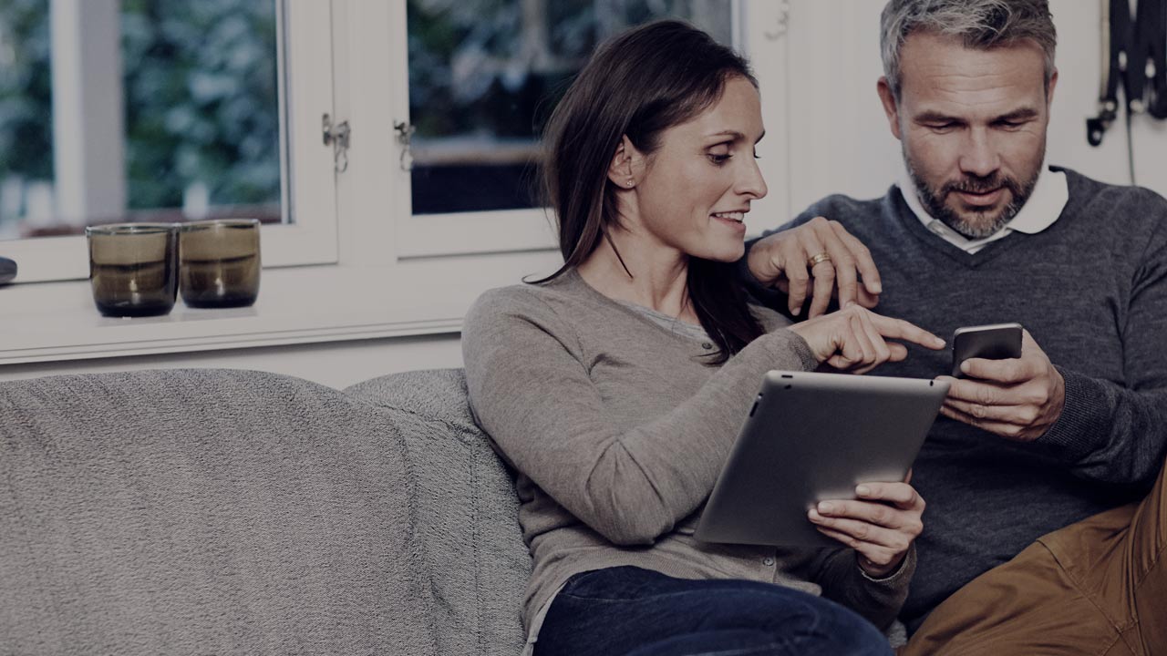 Couple in sofa with phone and tablet