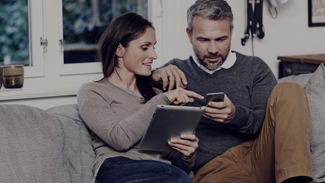 Couple in sofa with phone and tablet