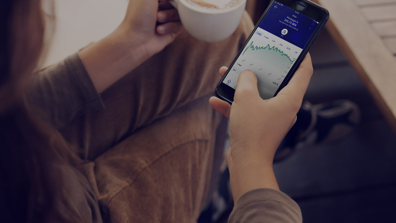 Woman looking at phone showing investments in the Nordea app