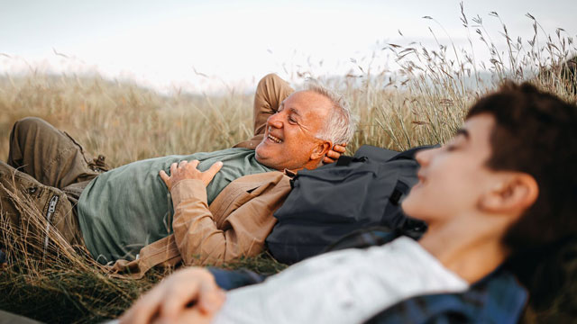 Grandad-and-grandson-laying-on-grass-and-relaxing-small